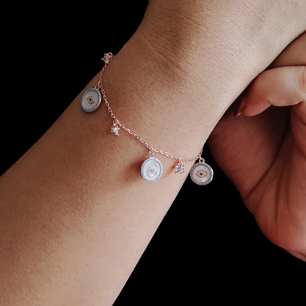 Evil eye charms bracelet in rose gold with mother of pearl, blue zircons, and protective charms